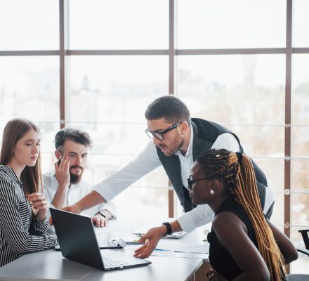 A diverse team collaborating around a laptop